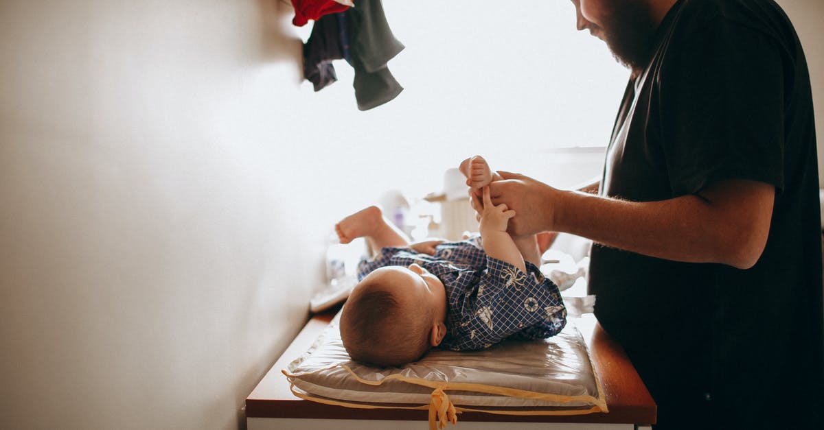 Flying with a baby, changing diapers onboard - Young father changing diaper of newborn baby