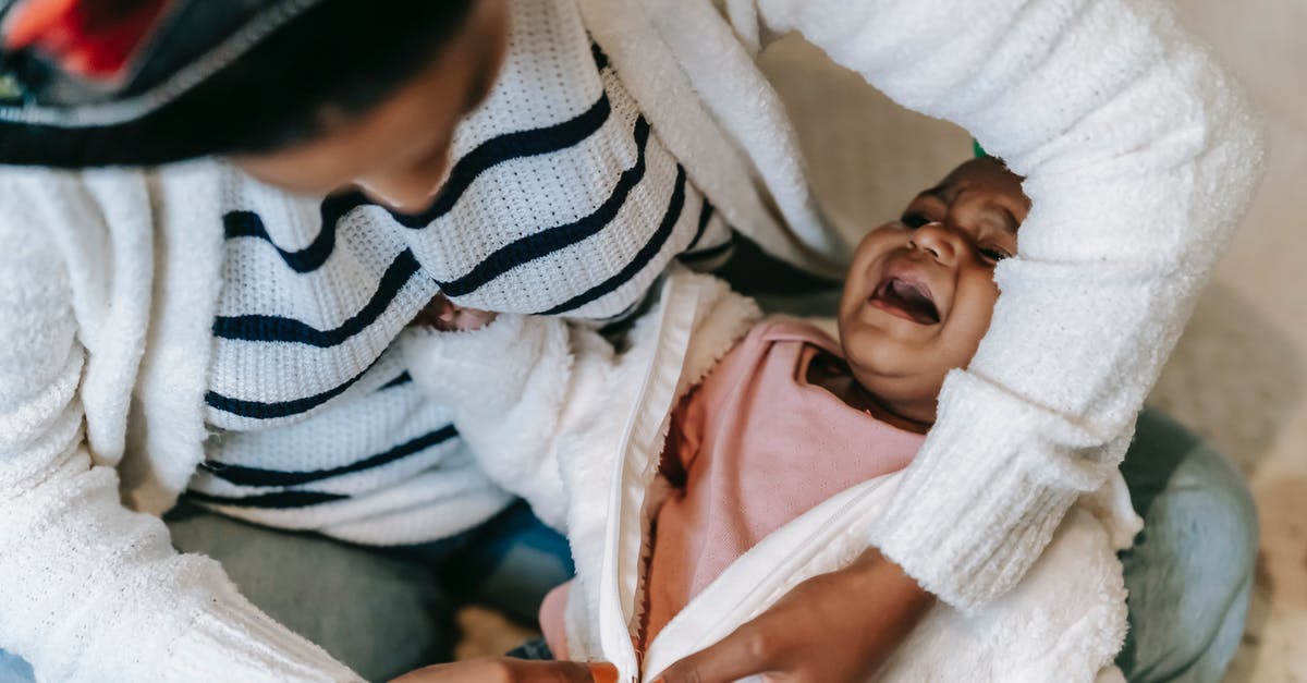 Flying with a baby, changing diapers onboard - A Mother Changing Her Baby's Clothes