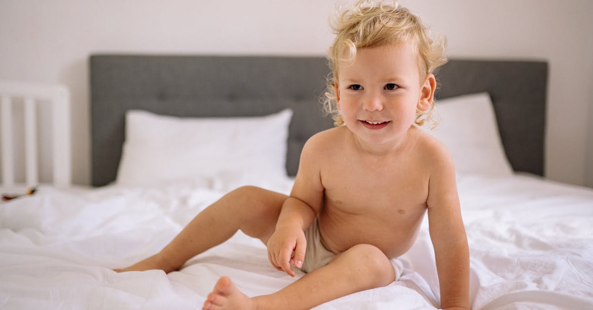 Flying with a baby, changing diapers onboard - Happy Toddler Sitting on Bed