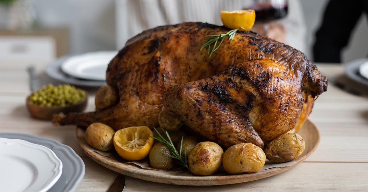 Food imports and exports from Turkey - From above of big turkey roasted with lemon and potatoes on round wooden tray placed on table for celebrating Thanksgiving Day