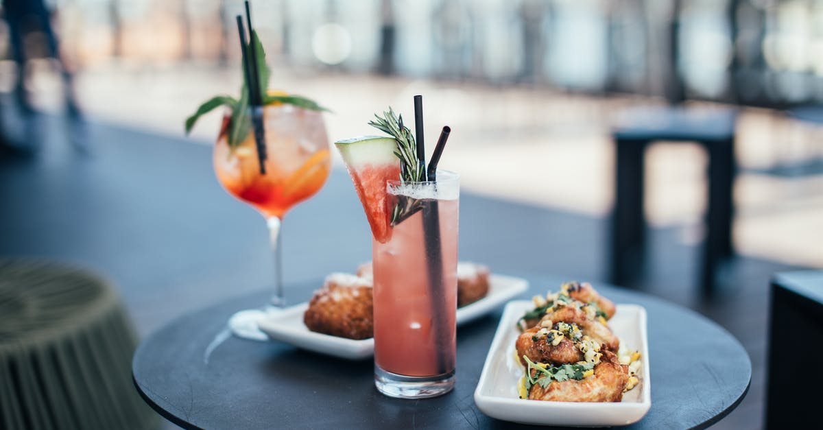 Food or drinks on VTA Light Rail - Glasses with colorful cocktails garnished with green herbs and straws with watermelon slice near white plates with delicious appetizers on round table in street restaurant in daytime