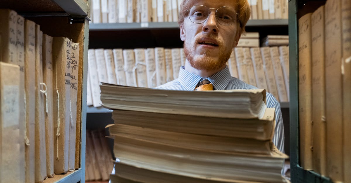 Foreign storage of a carry-on - A Man Carrying a Pile of Documents