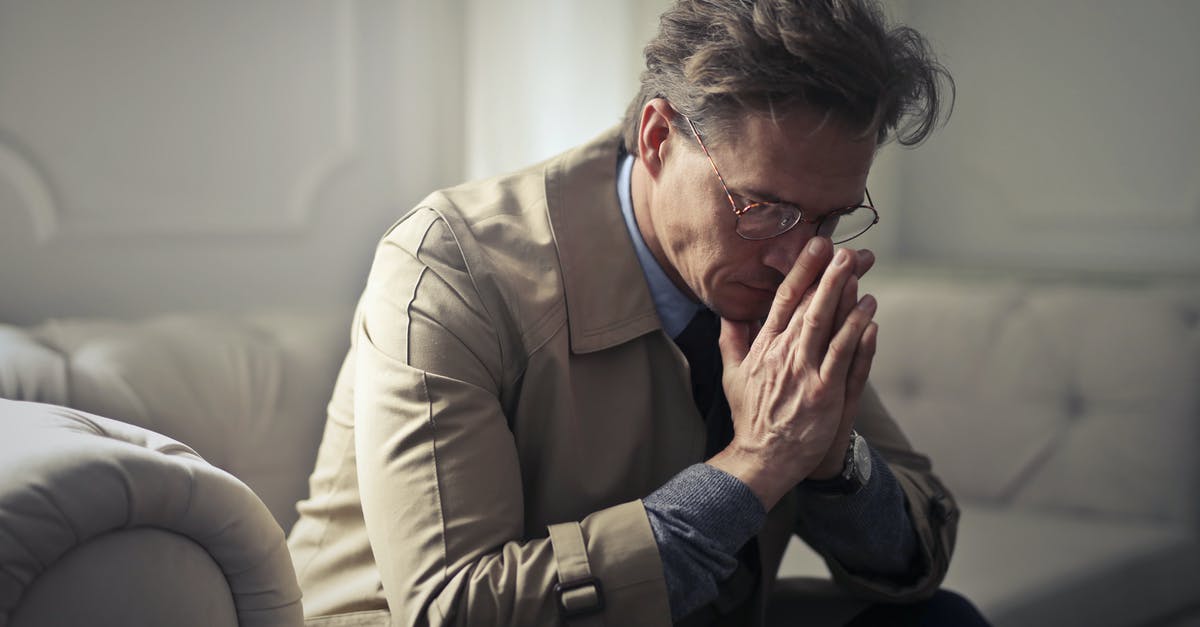 Formal obligation letter or family member? - Side view of upset male entrepreneur in formal wear sitting on couch in modern living room and contemplating about financial problems while leaning on hands and looking down