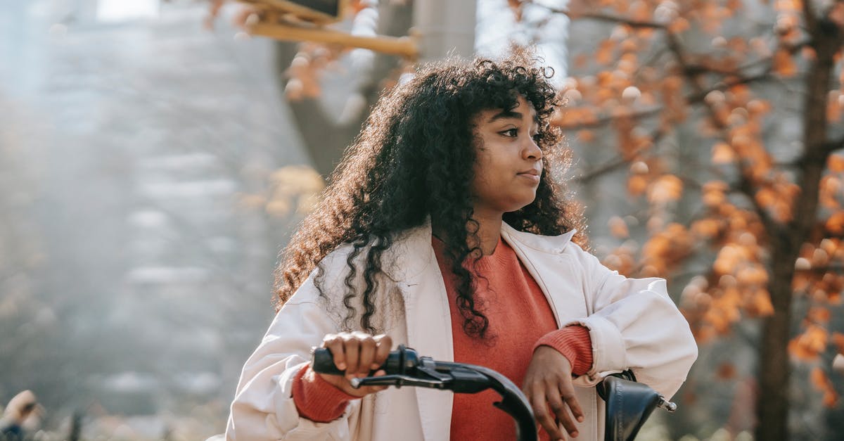 Found a lonely bike in Germany, what to do? [closed] - Dreamy young black lady in casual outfit looking away on street with bike in town in sunny day near tree with orange leaves and traffic light