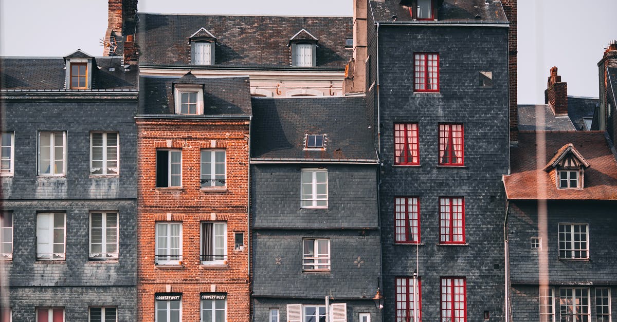 France Switzerland trip [closed] - Row of old historic stone residential houses with chimneys and windows located in Honfleur town on sunny day