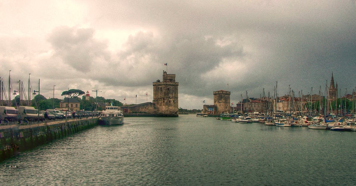 France Visa Query - Brown Concrete Building Near Body of Water Under Cloudy Sky