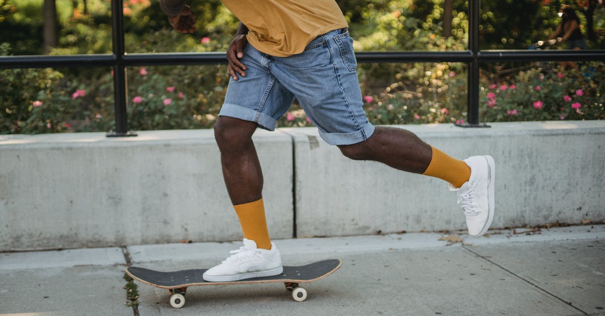 Free park and ride between Siegburg and airport DUS? - Side view of crop faceless black man skater in trendy outfit riding skateboard on street near park in sunny day