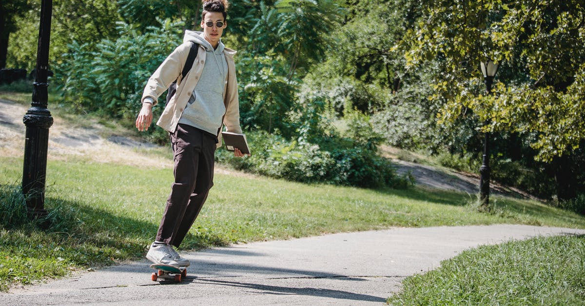 Free park and ride between Siegburg and airport DUS? - Full body of stylish active young ethnic male millennial in trendy outfit and sunglasses riding skateboard on pathway in park after studies