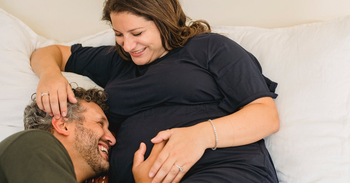 French spouse visa when full name changed after marriage - Laughing pregnant couple lying together on bed and having fun