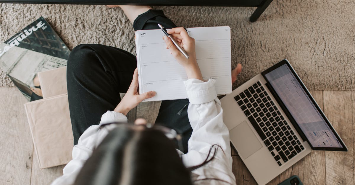 French student in Canada: going back home from NYC - Top view of anonymous woman in casual wear sitting on floor with laptop and smartphone and creating plan on notebook while resting during break in modern living room