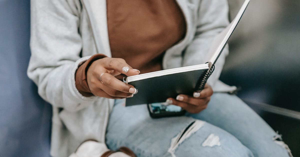 Frequent short-term student visa - UK/US citizen - Crop unrecognizable young ethnic woman in casual clothes reading notepad near backpack and phone while sitting in subway train