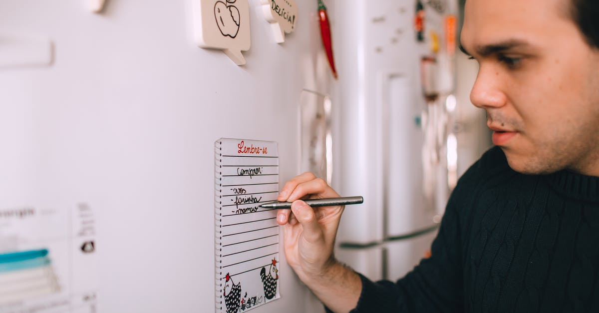 Fridge magnets in San Francisco! - Young man writing reminder on fridge note