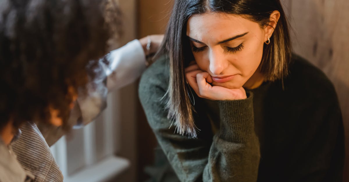 Friend needs help in Turkey - Crop woman tapping shoulder and comforting upset female friend while sitting at home together