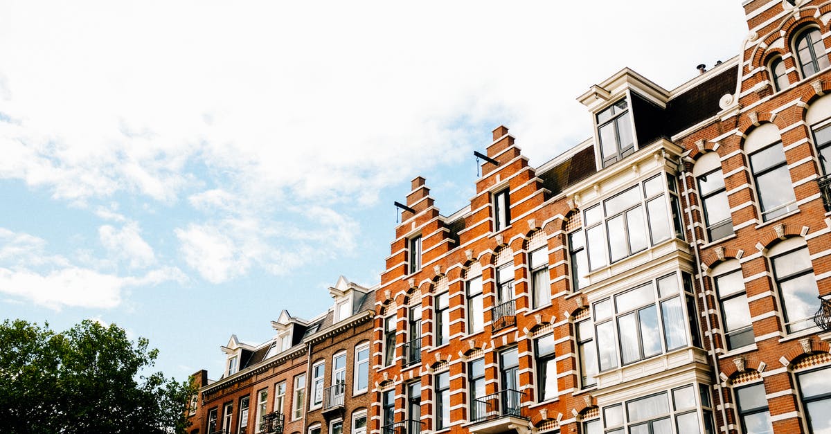 From Amsterdam (Netherlands) to Lima (Peru) by flight? - Low angle exterior of contemporary narrow apartment buildings of brown color with white decorative elements in Dutch style