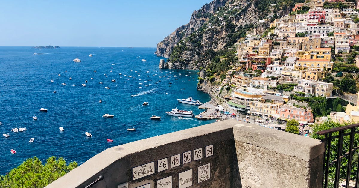 From North of Italy to Greece via ship - View from balcony on Positano town on tropical Amalfi coast with boats sailing at sea on sunny day