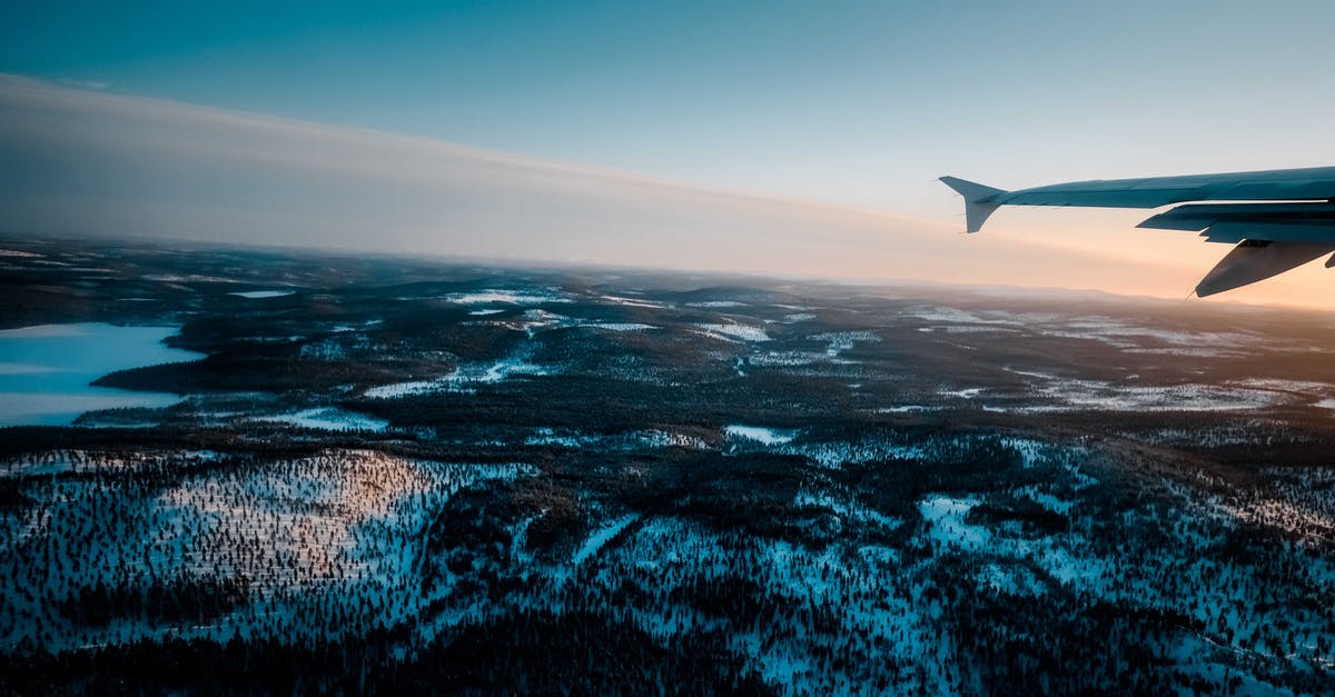 From Puno to La Paz through Lake Titicaca? - Plane flying over snowy terrain with trees and lake at sundown