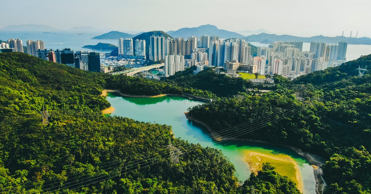 From Shenzhen to Hong Kong as a Western traveller? - Picturesque scenery of reservoir located in hilly terrain covered by lush green trees near Victoria Harbour with modern skyscrapers in Hong Kong