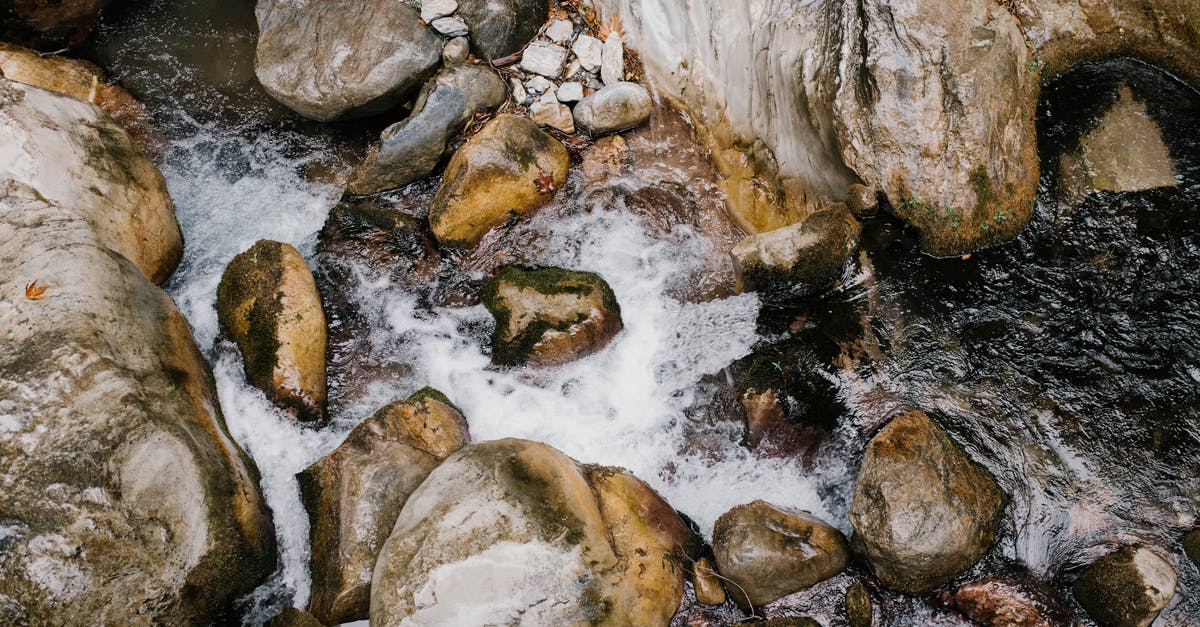 From UK to Chile through Atlanta [duplicate] - From above of fresh fast curvy stream of mountain water flowing through big slick stones