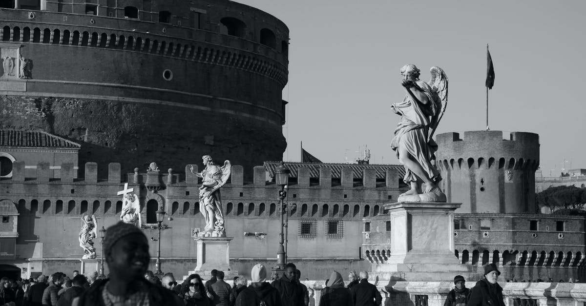 Gambian in Italy wants to visit UK [duplicate] - Black and white crowd of diverse travelers walking on bridge with marble statues near famous ancient Castel Sant Angelo on sunny day in Rome