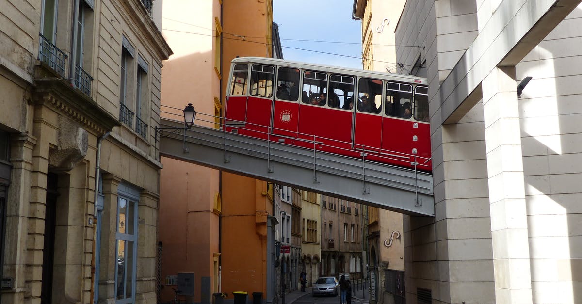 Gare de Lyon to CDG on November 3-4, 2018 - Aged red cable car driving in old district of Lyon between shabby buildings on sunny day