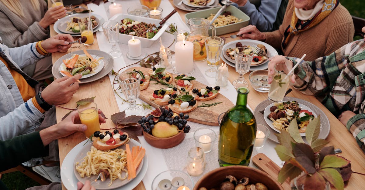 German family reunion (long term) visa transit through Schengen country - From above crop people enjoying festive dinner with snacks at garden table with candles burning