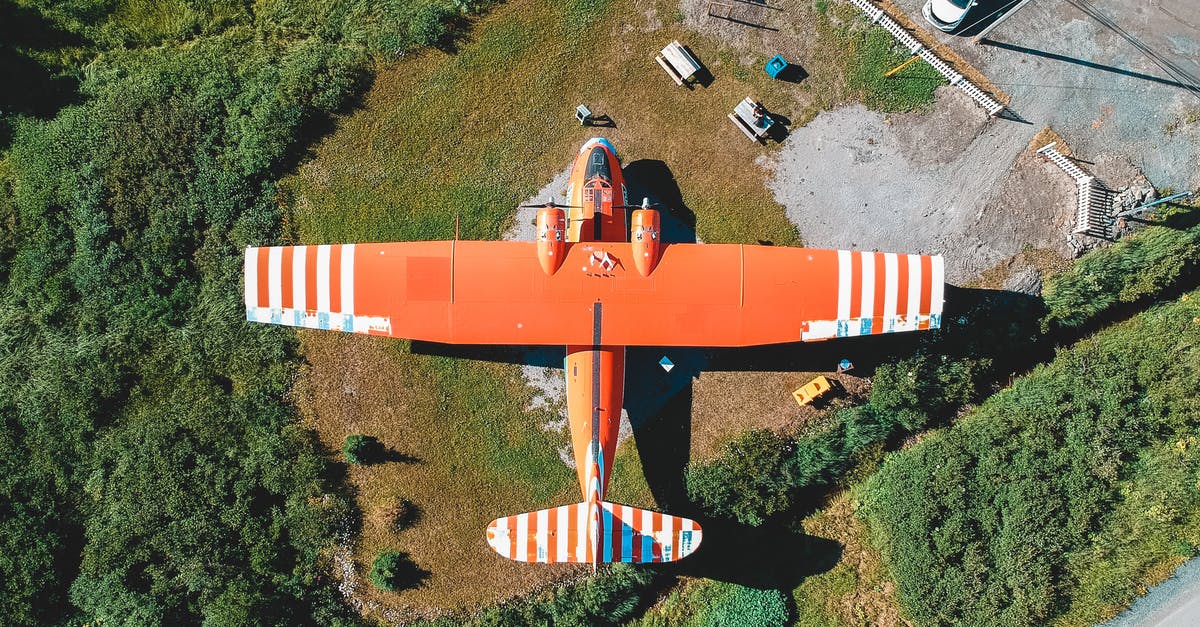 Get into a country without booked flight [duplicate] - Aerial view of colorful orange airplane on green meadow in countryside in sunlight