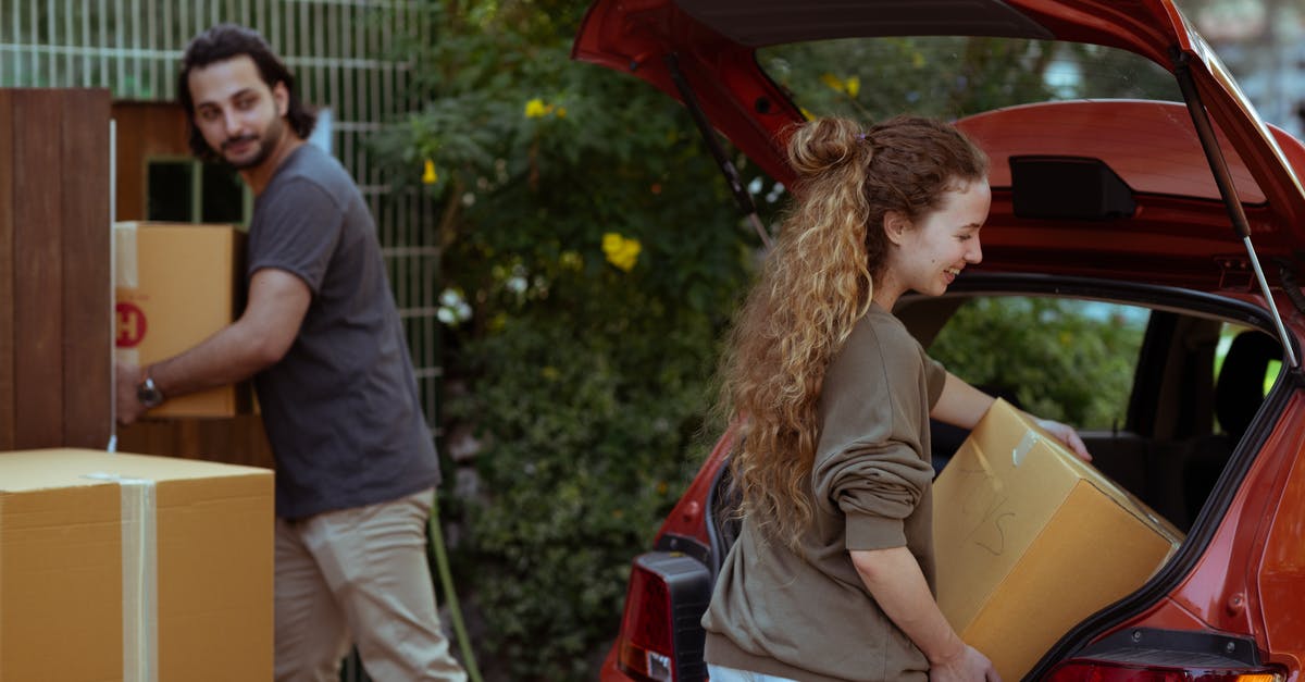 Getting a UK visitor visa for my girlfriend - Couple getting carton boxes out of red car while relocating in new home