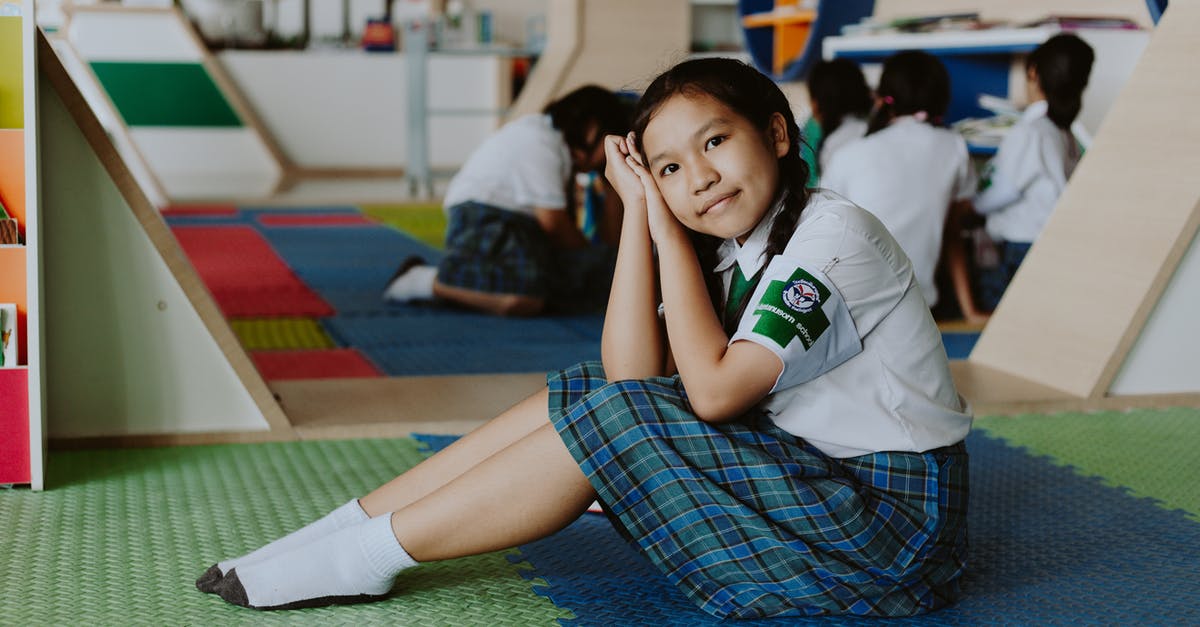 Getting around in Thailand without knowing Thai - Thai Girl in School Uniform Sitting on Ground Looking at Camera