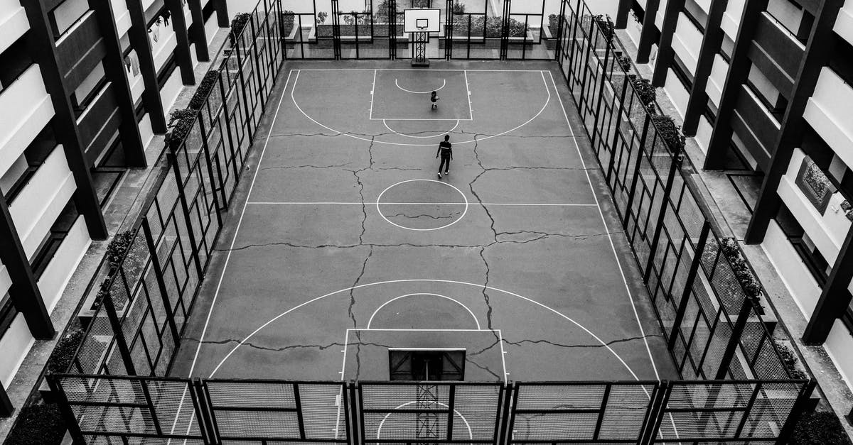 Getting FBI challenge coins from FBI field offices / resident agencies? [closed] - From above of black and white of people playing on public sports ground for team games with basketball hoops fenced with metal barrier