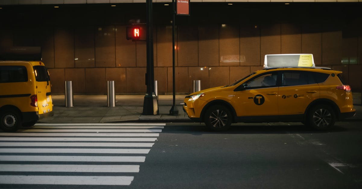 Getting from Pudong Airport to Pudong Avenue area at night - Modern shiny yellow SUV taxi car stopped near traffic light at zebra crossing in evening