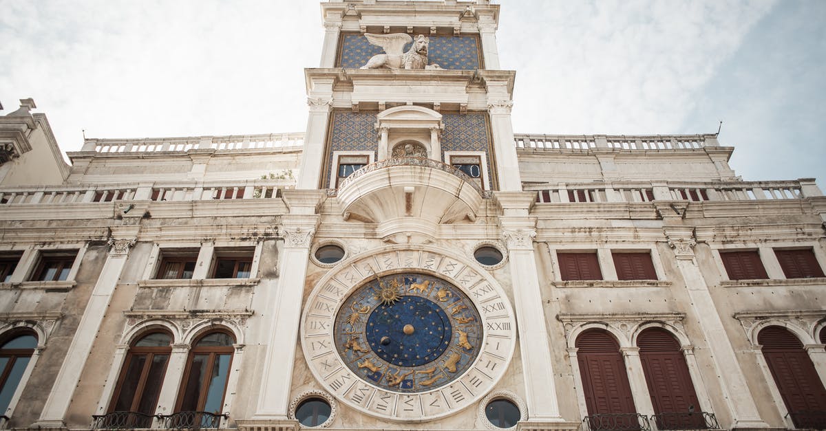 Getting from Split, Croatia to Venice, Italy - From below amazing view of famous old St. Marks Clocktower with cozy windows and stucco work against blue sky