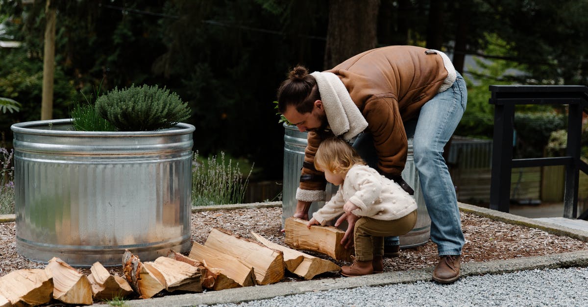 Getting outside of touristy activities in Hawaii [closed] - Side view of little girl and man wearing casual clothes looking down and putting firewood on ground while spending time in yard together