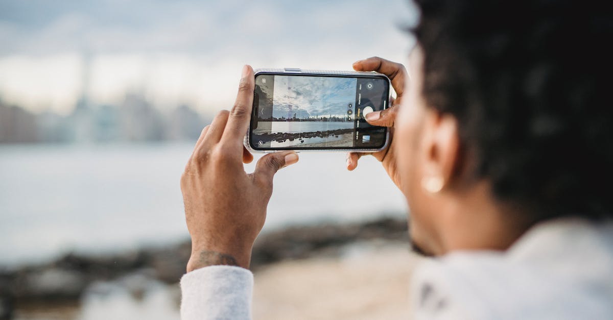 Getting permission for photography from Yamuna river coast - Back view of crop African American male taking picture on mobile phone of coastal city located on river bank