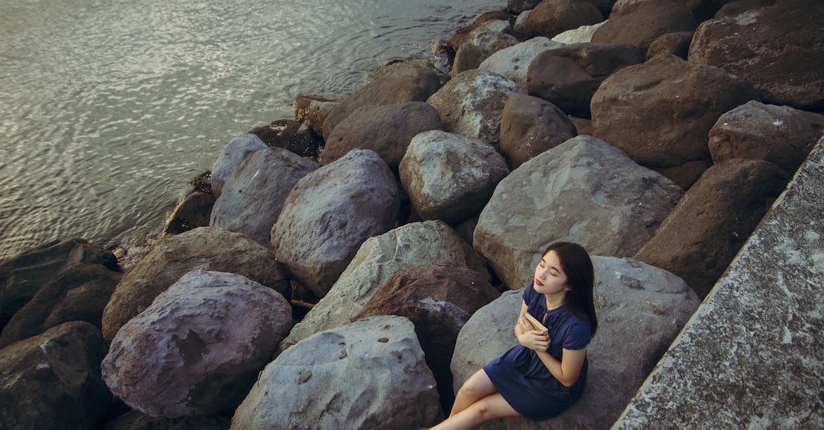 Getting permission for photography from Yamuna river coast - Woman in Blue Dress Sitting on Rock Near Body of Water