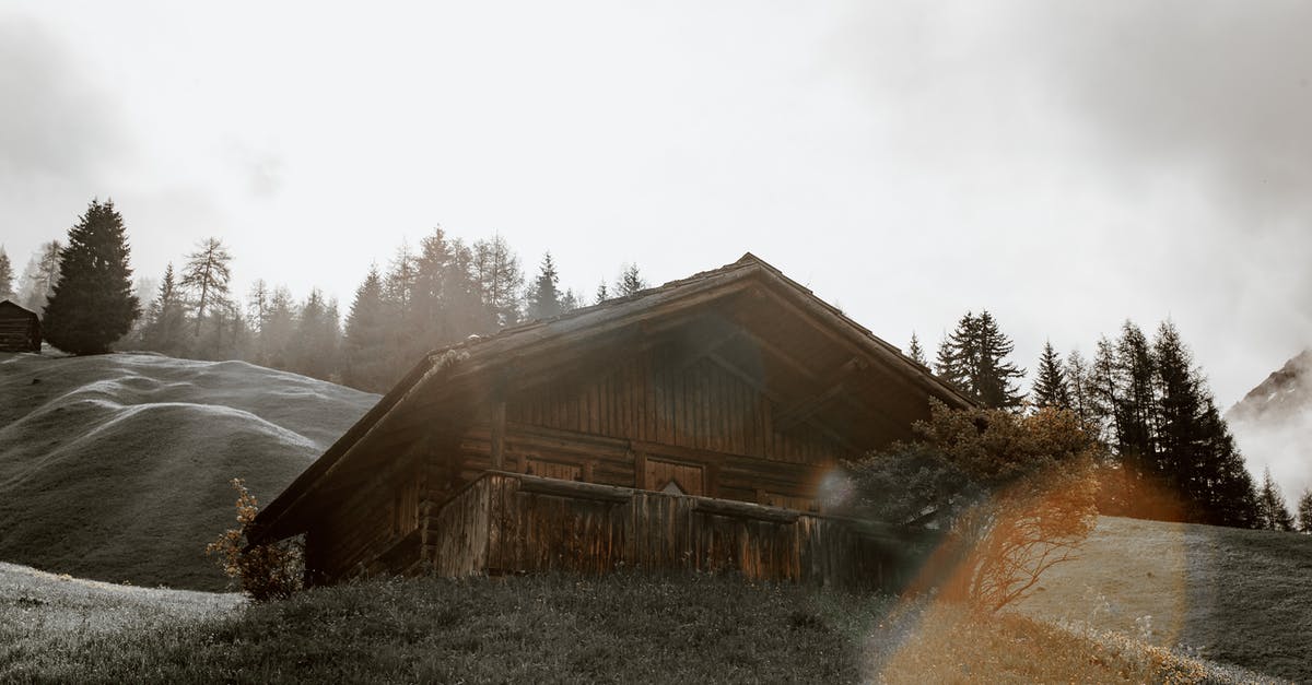 Getting to Shatili village from Tbilisi? - Low angle of small weathered village house located on green hilly valley amidst coniferous trees on overcast day