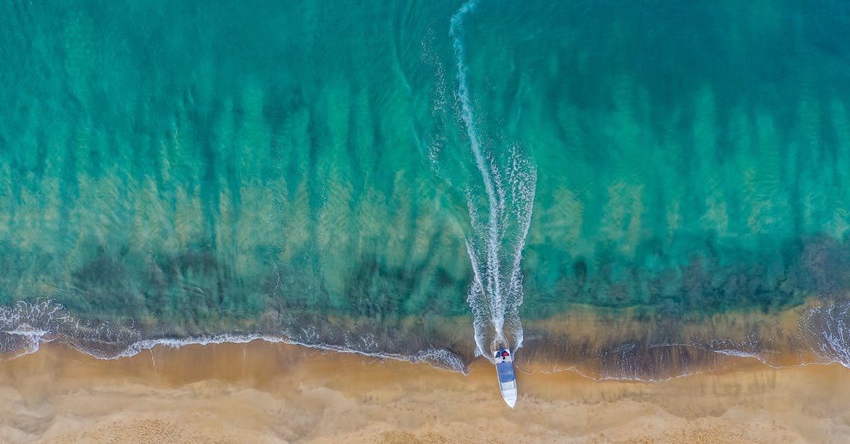 Getting to the West Coast Trail without a car - Drone view of calm sea water running on sandy remote sand with motorboat leaving trail while mooring