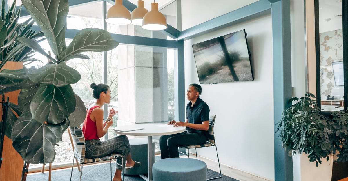 Getting US visa for a job meeting - A Man and Woman Sitting on the Chair while Looking at Each Other