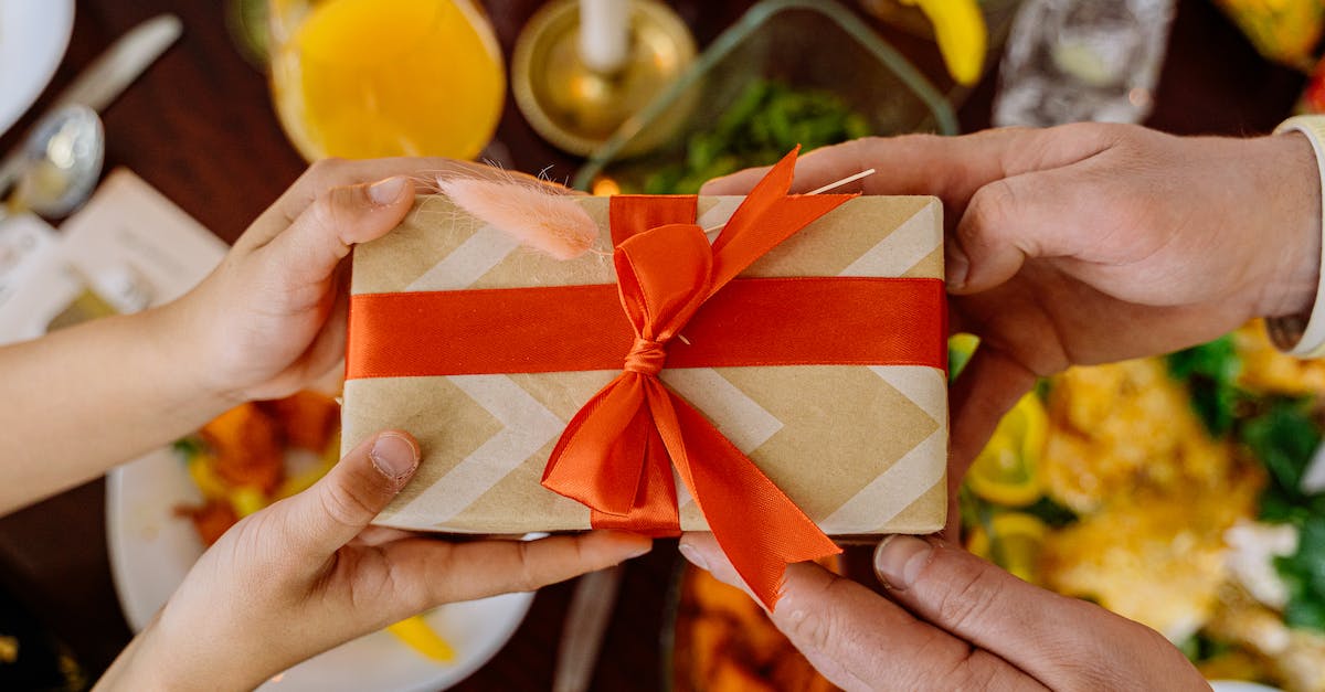 Gift giving in Korea: Do I have to wrap snacks? - Close-Up Shot of Two People Holding a Wrapped Gift with a Ribbon