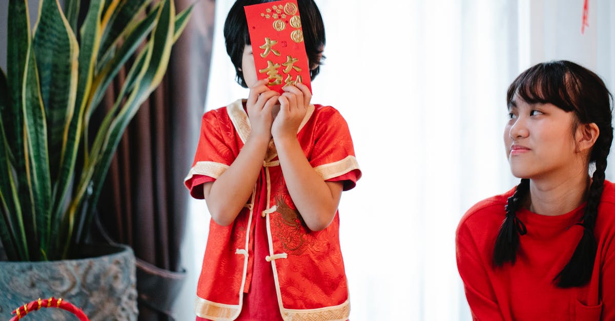 Gifts for Chinese hosts? - Unrecognizable boy with envelope against Asian sister during festive event