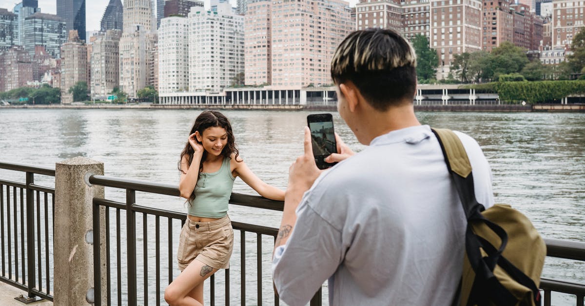 Girlfriend from Hong Kong told interviewer for her B2 visa to the US that we were not dating - Young man photographing girlfriend on smartphone during date in city downtown near river Girlfriend from Hong Kong told interviewer for her B2 visa to the US that we were not dating - Young man photographing girlfriend on smartphone during date in city downtown near river