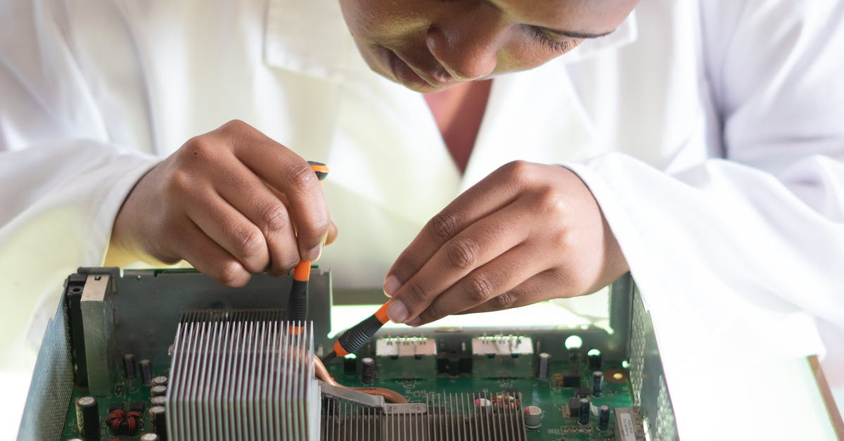 go to check-in for visa check and boarding card - Concentrated African American technician wearing lab coat and conducting expertise of motherboard by using screwdrivers while working in service center