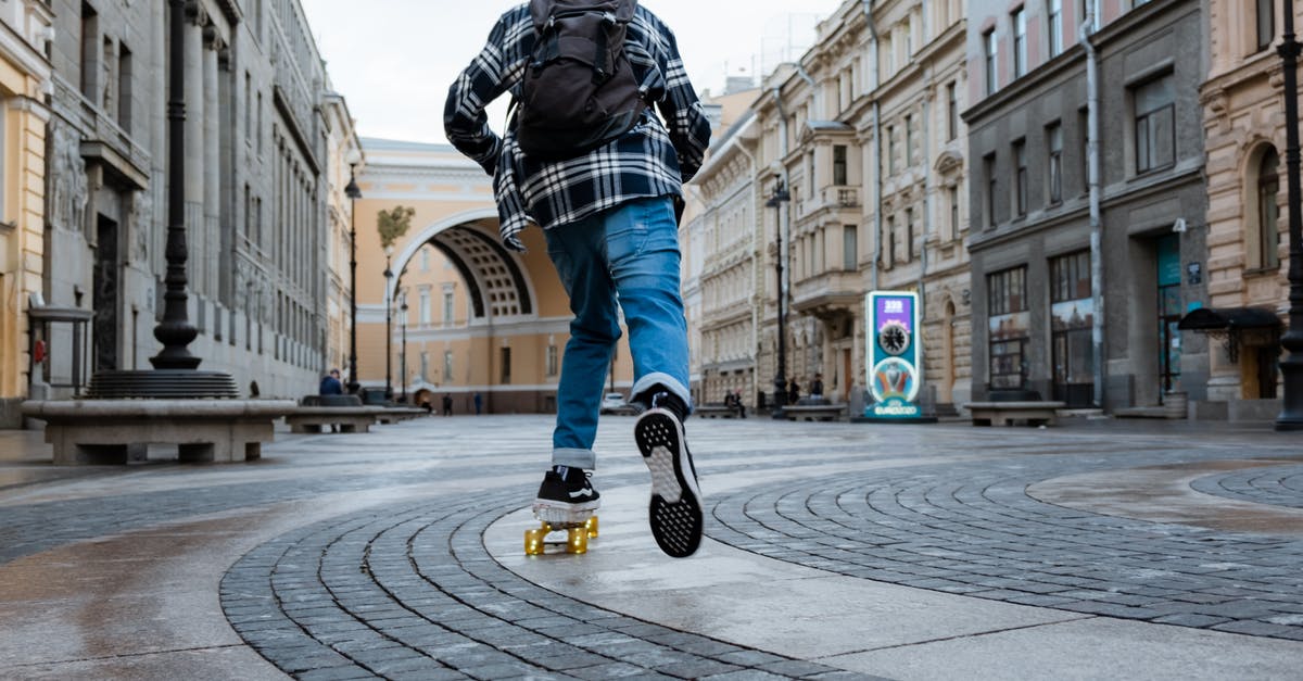 Going back to Russia with another passport (maybe) - Man in Black Leather Jacket and Blue Denim Jeans Walking on Pedestrian Lane