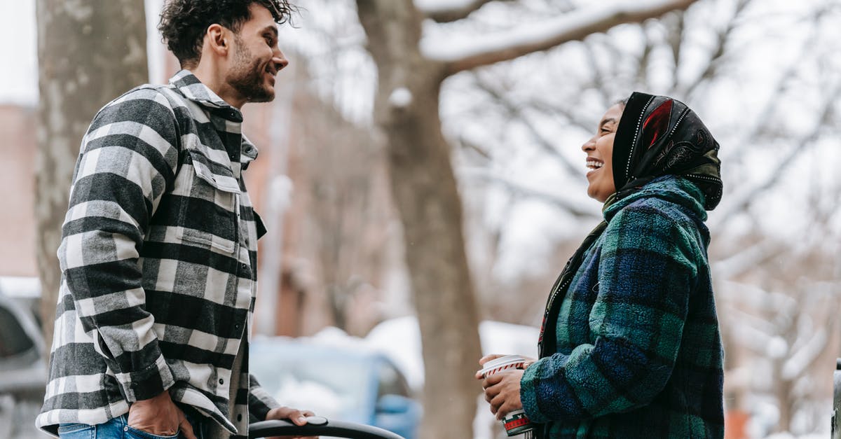 Going from Berlin to Munich by car [closed] - Low angle side view of cheerful ethnic couple laughing happily standing on roadside in snowy city