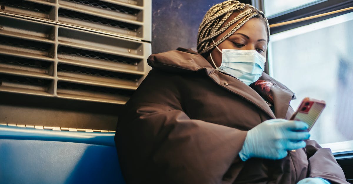 Greyhound Canada - How do I book bus tickets online for passengers with multiple discounts? - African American woman with phone riding bus in pandemic Greyhound Canada - How do I book bus tickets online for passengers with multiple discounts? - African American woman with phone riding bus in pandemic