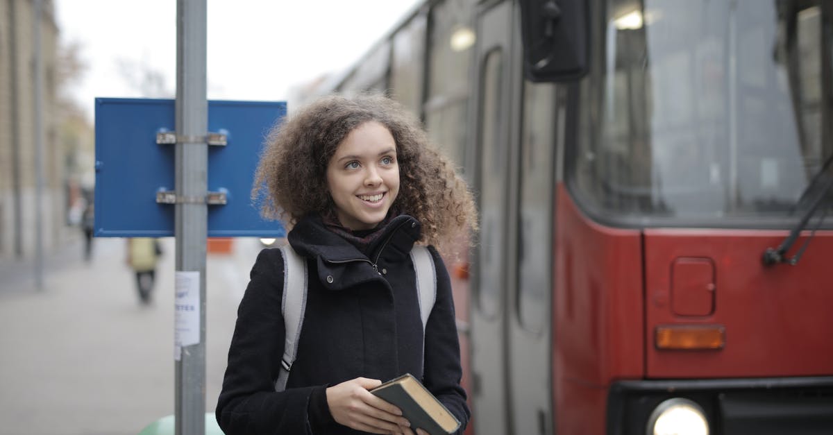 Greyhound Canada - How do I book bus tickets online for passengers with multiple discounts? - Cheerful young lady with book waiting for bus on street Greyhound Canada - How do I book bus tickets online for passengers with multiple discounts? - Cheerful young lady with book waiting for bus on street