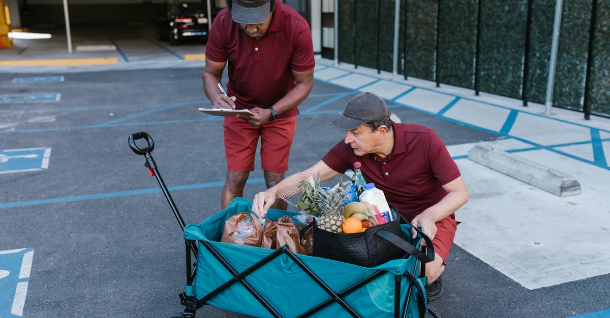 Grocery Delivery Services in Denmark - Man in Red Crew Neck T-shirt and Blue Denim Jeans Pushing a Cart With Fruits