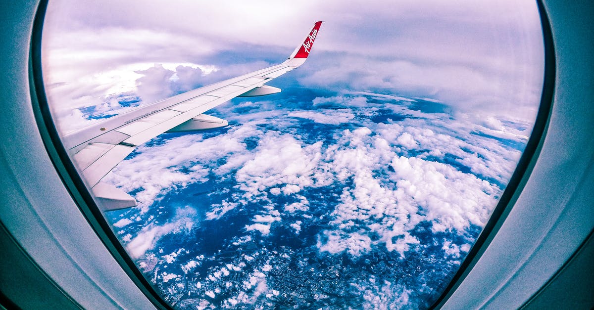 Ground transport and overnight stay - Wide angle of rocky ground through cloudy sky and plane wing from window of aircraft