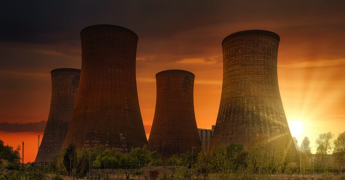 Guided tours of Japanese nuclear power plants - Exterior of huge cooling towers located in contemporary atomic power plant against bright setting sun under dramatic dark sky