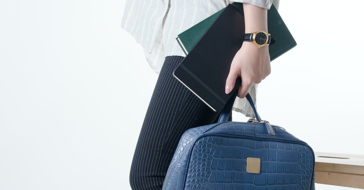 Hand luggage - multiple airlines: Which Rules apply? - Hand with Notebooks and Blue Hand Bag