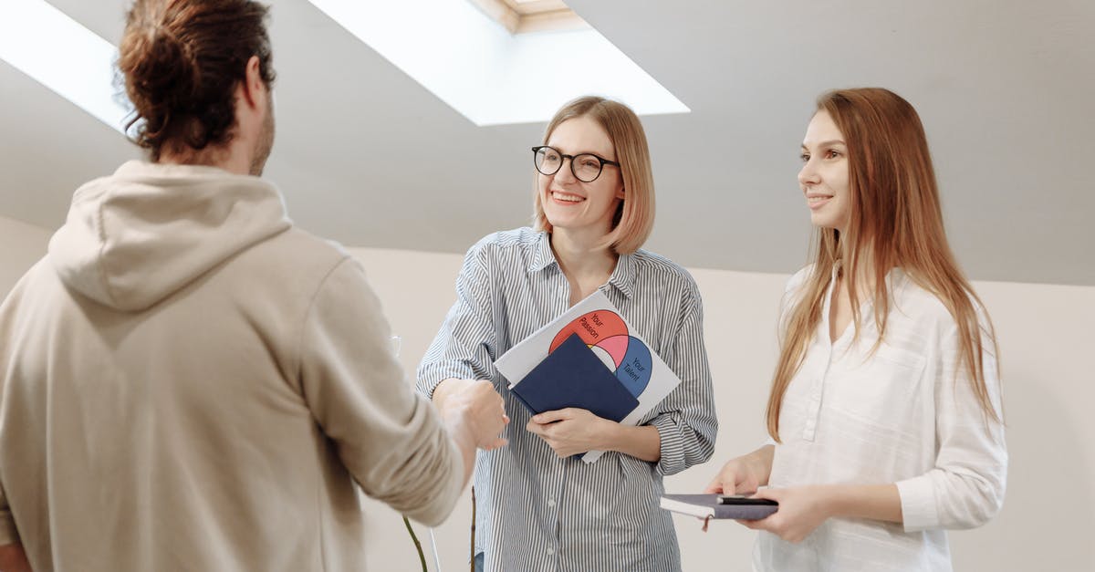 Handshake while holding own right elbow - Women Holding Notebooks Talking to a Man in Hoodie